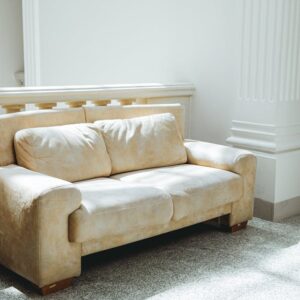 A luxurious beige sofa in a sunlit room with classic architectural details.